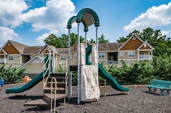 A playground with a slide and climbing equipment in front of a row of houses